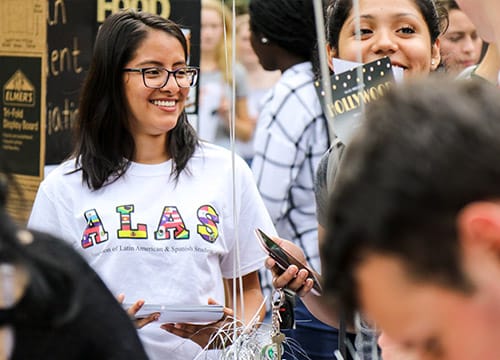 Students smiling and wearing a shirt that reads ALAS - Association of Latin American & Spanish students