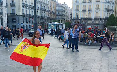 A student poses with the flag of Spain in Alcal谩, Spain