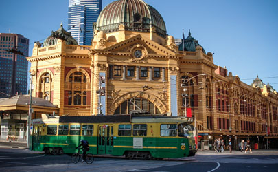 A streetcar passes in front of a classical style building in downtown Melbourne, Australia